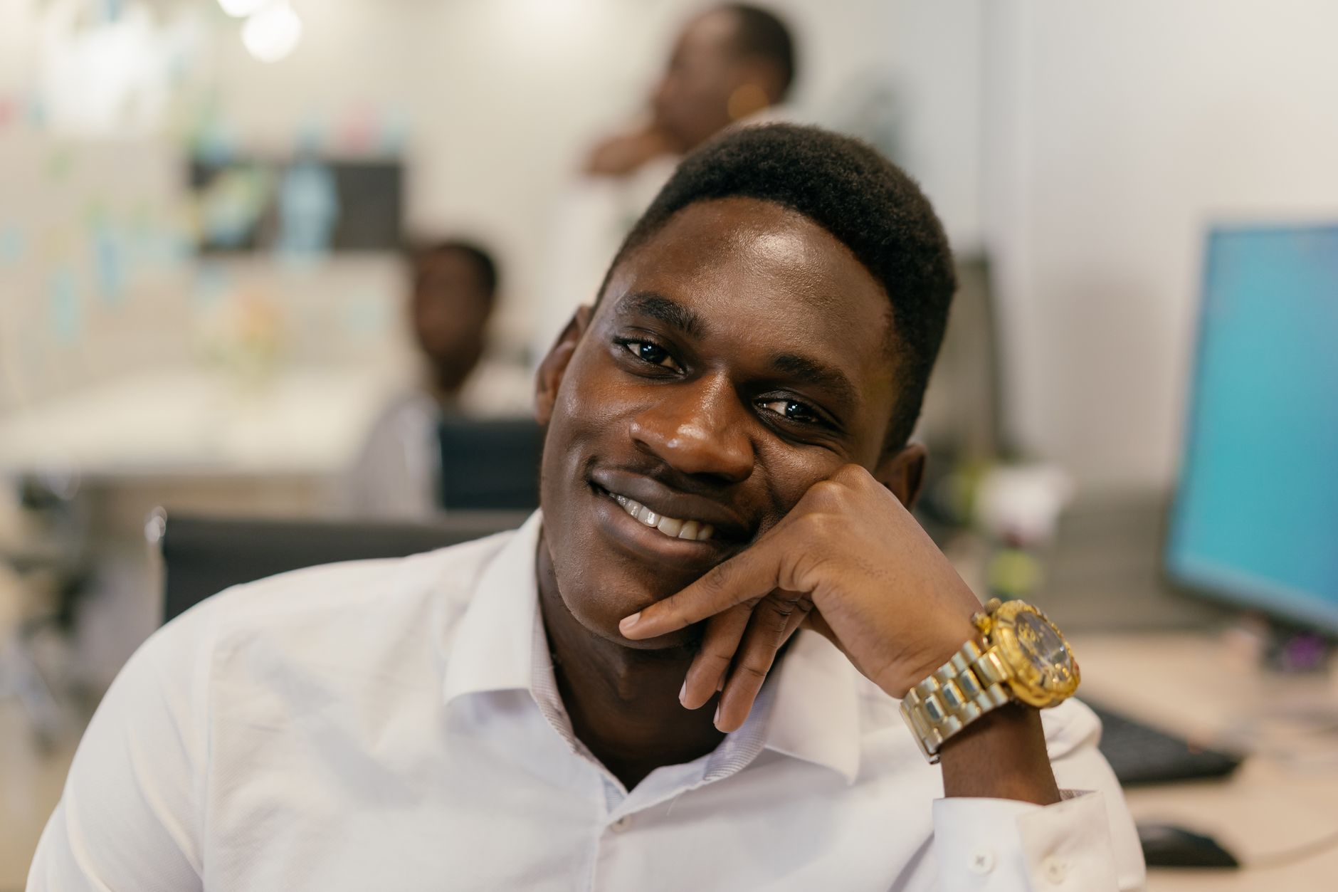Gros plan d'un homme souriant en chemise blanche, détendu dans un environnement de bureau.